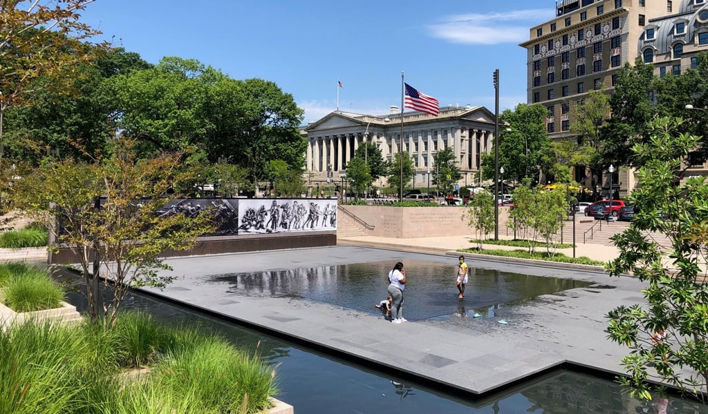 People play in the water feature at the World War I Memorial site in Washington, DC. 