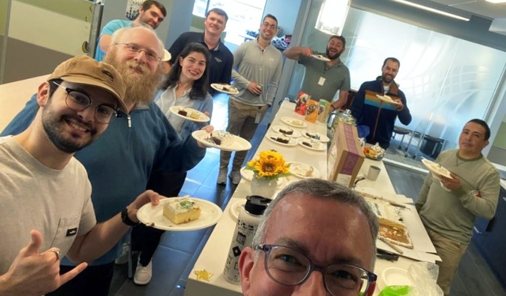 VHBers in the Tysons office smile while eating their cake.