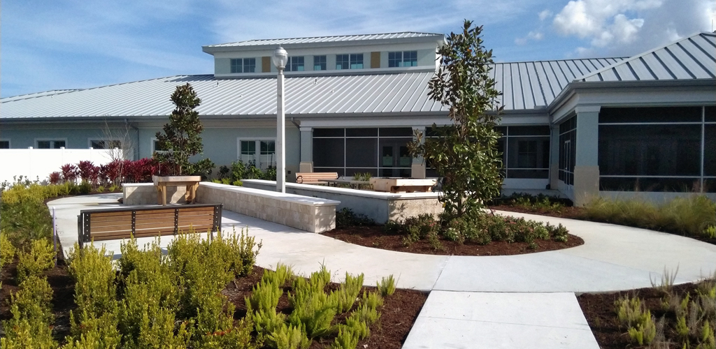 A garden, bench and path in front of a one-story Veterans nursing home