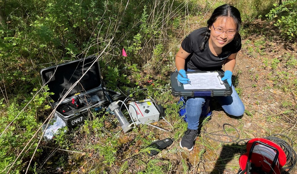 VHB intern kneeling on the ground holding a tablet and using groundwater sampling equipment