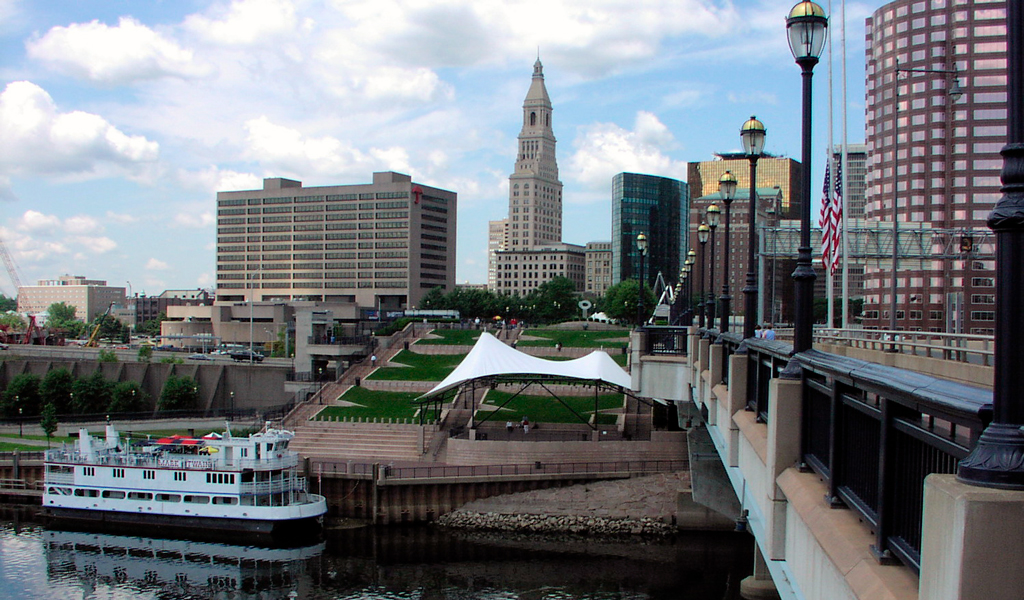 Bridge over river with city skyline in background.