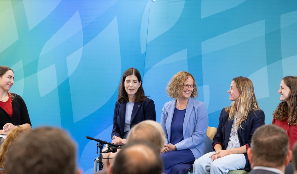 Five women on high stools engaged in a panel discussion.