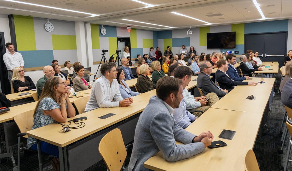 A classroom-style conference room filled with people.