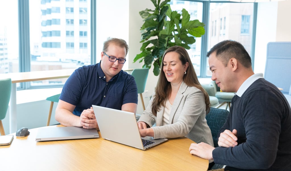 Gavin Graham and colleagues brainstorming in the office casual space near the shuffleboard table.