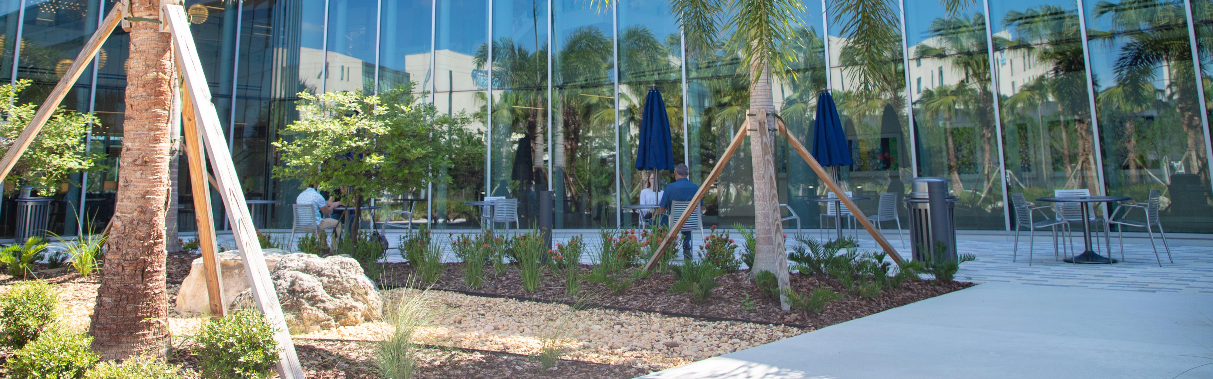 People sitting at outdoor dining tables beside a new hospital