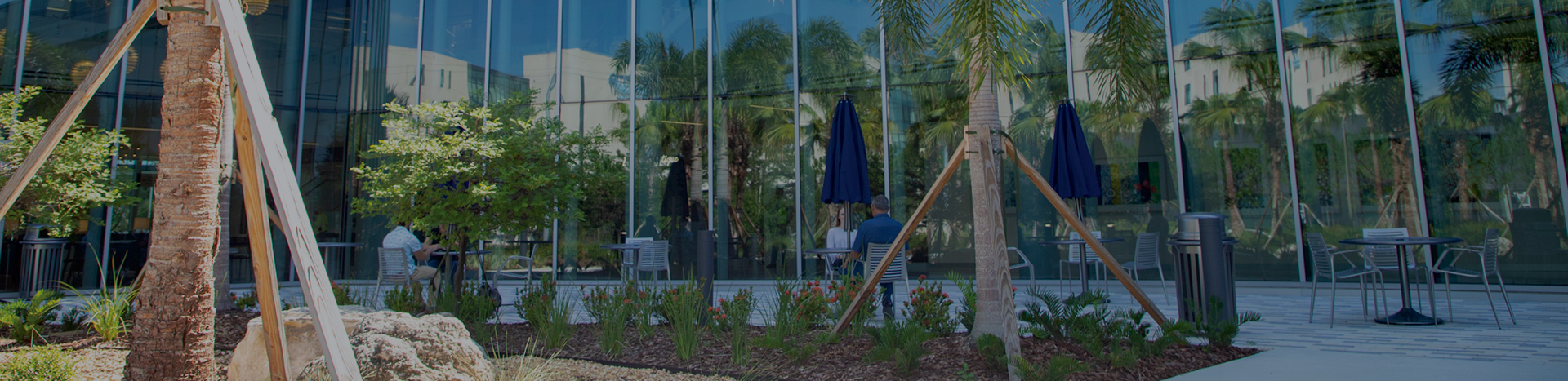 People sitting at outdoor dining tables beside a new hospital