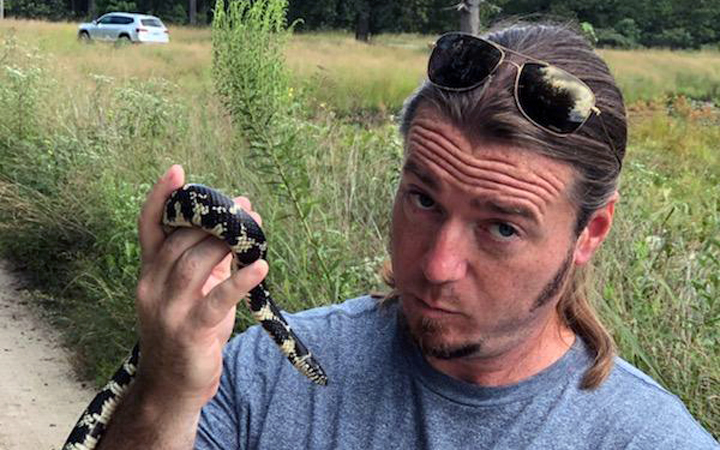 David Cooper safely holding and examining snakes