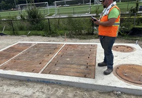 A person stands on the recently installed Contech Jellyfish filter used to clean water before it leaves the site.