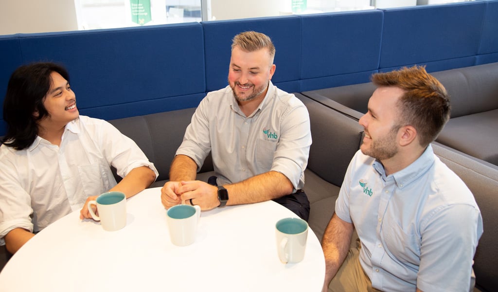 J.R. Hopson talking with two colleagues over coffee in the Charlotte office lounge.