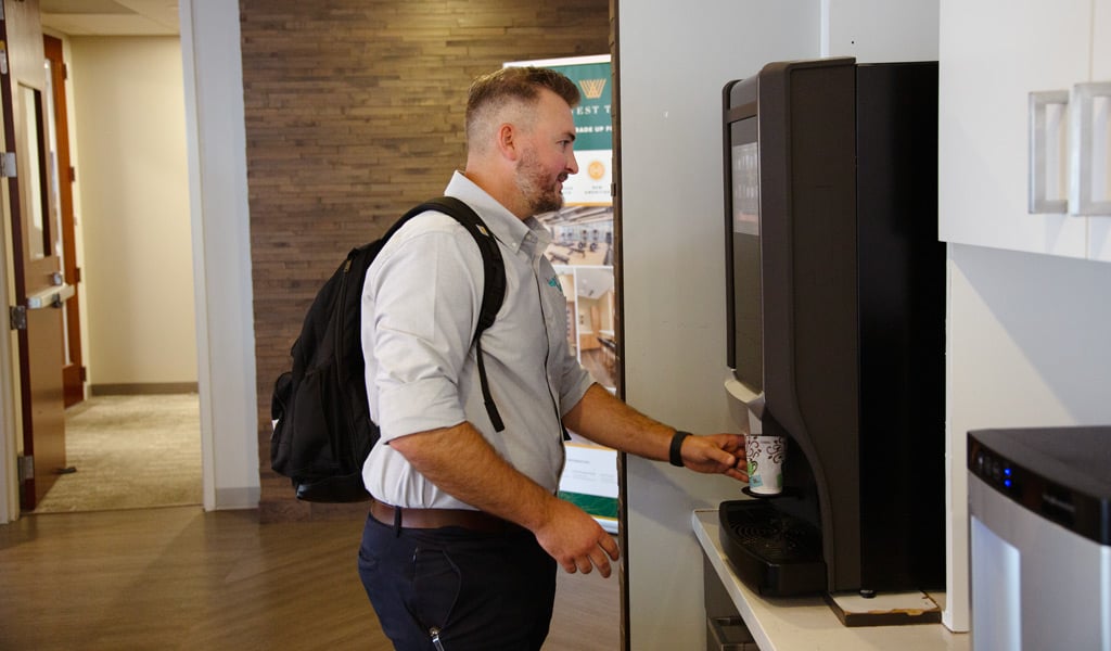J.R. Hopson fills a cup at the coffee machine after arriving at VHB's Charlotte office.