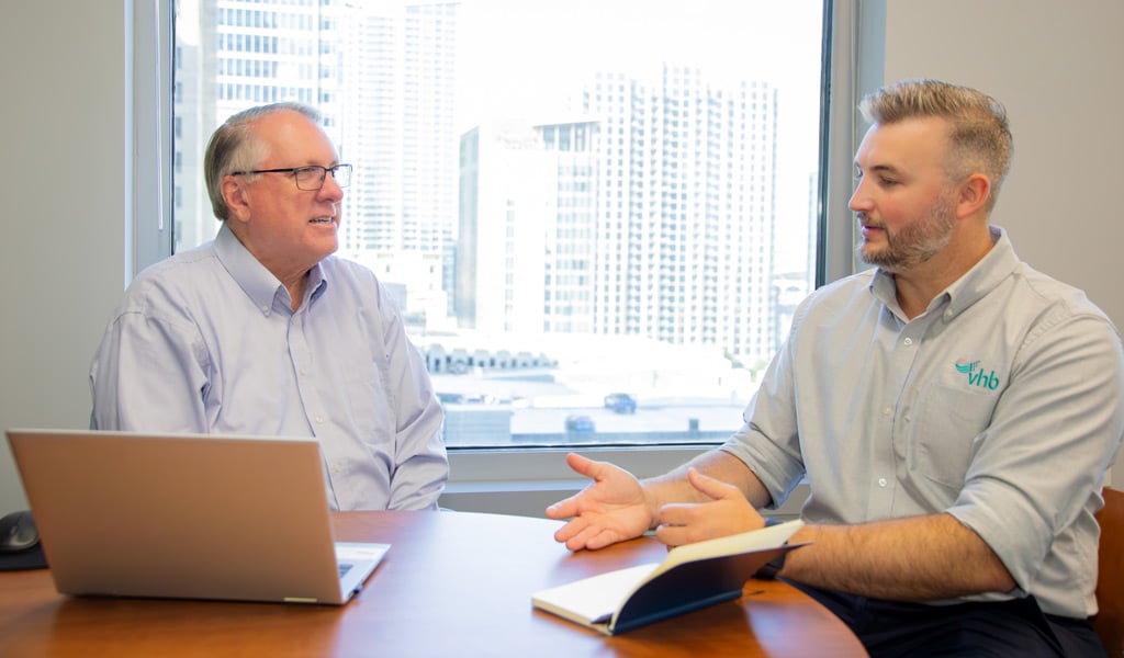 J.R. Hopson in conversation with Charlotte Managing Director John Muth in an office.