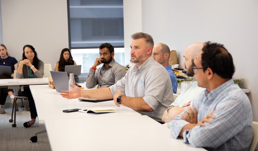 J.R. Hopson speaking during a leadership discussion with colleagues seated around a conference Image.