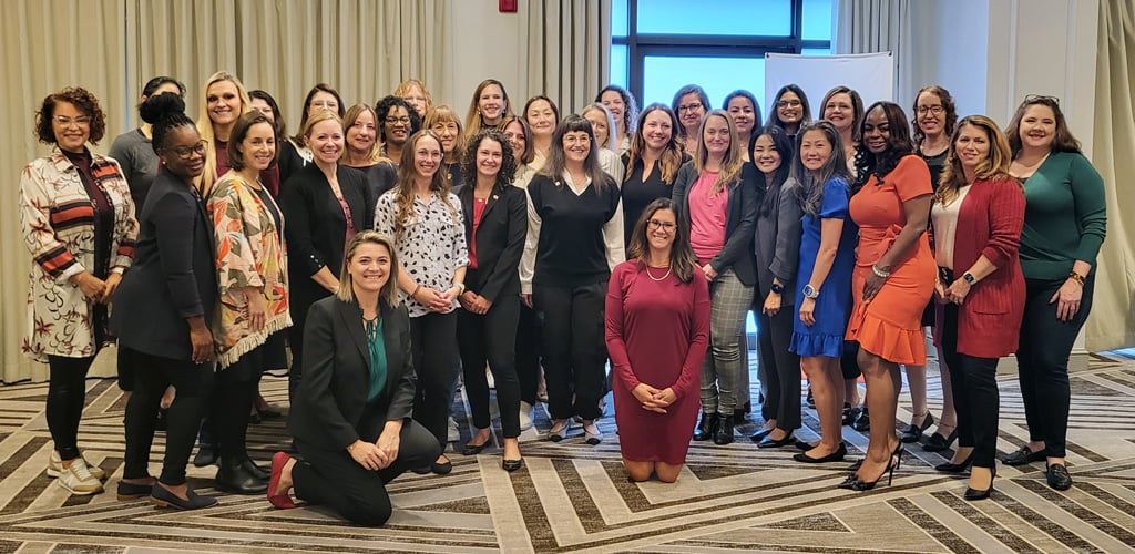 A large group of women, standing and kneeling in a conference room