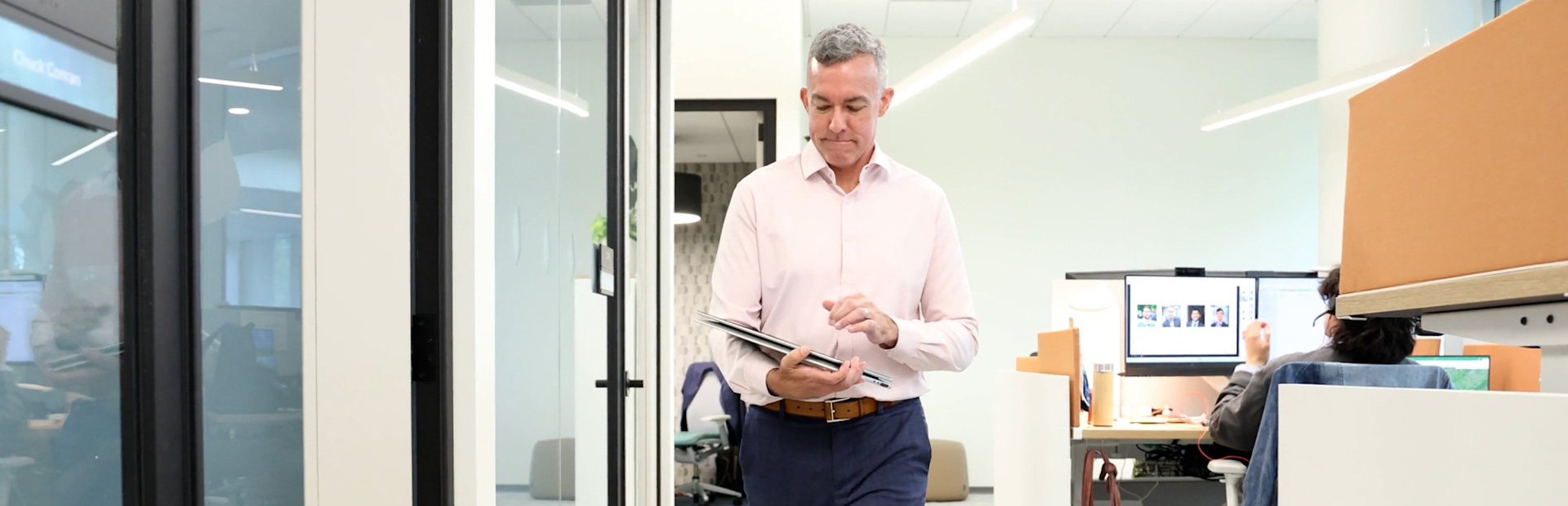 Joe Wanat walks down a VHB office hallway while viewing a tablet.