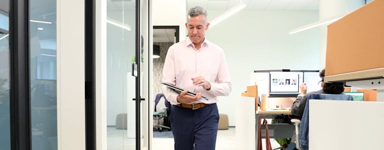 Joe Wanat walks down a VHB office hallway while viewing a tablet.