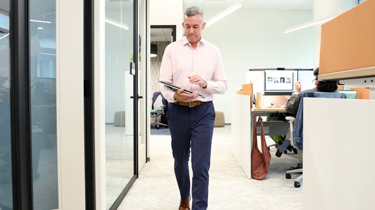 Joe Wanat walks down a VHB office hallway while viewing a tablet.