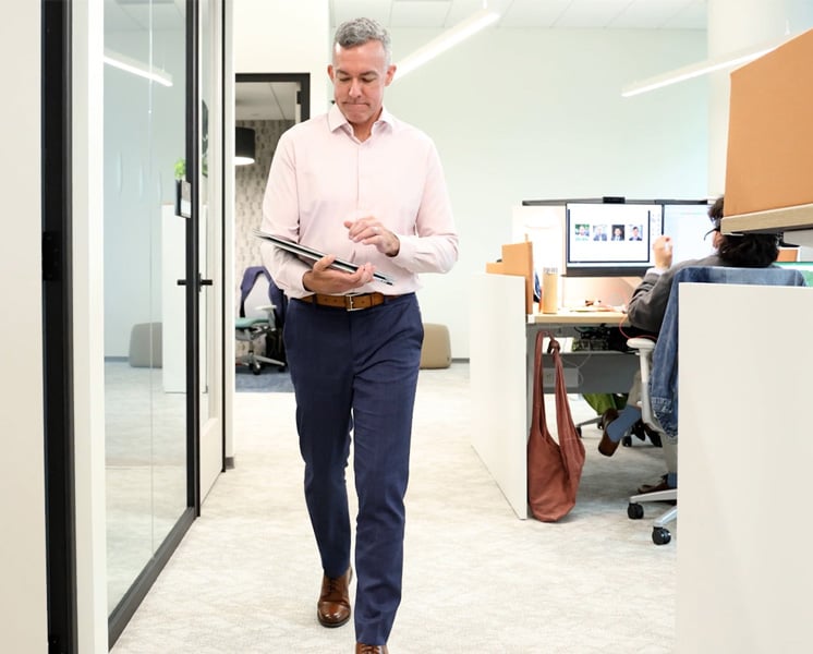 Joe Wanat walks down a VHB office hallway while viewing a tablet. 