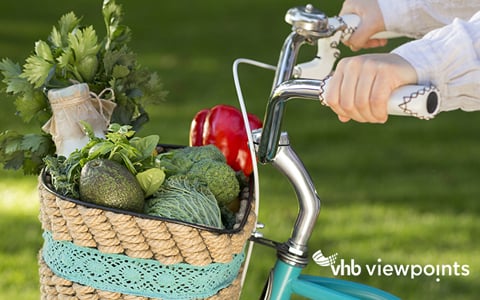Woman ride a bike with full basket of fresh vegetables