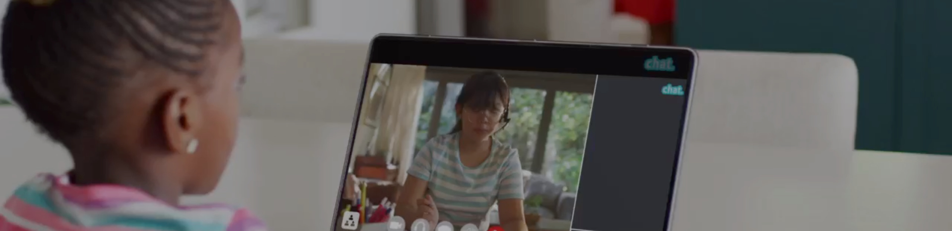 A young girl uses a laptop at a kitchen table.