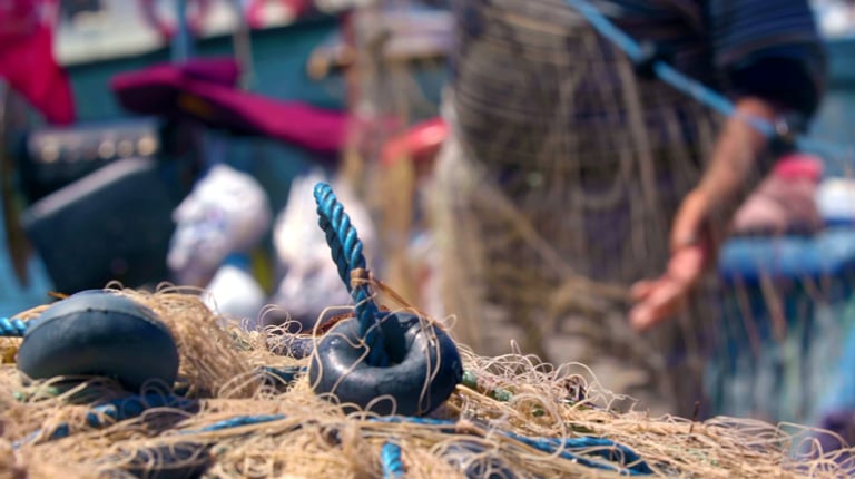A waterman prepares fishing nets in a port.