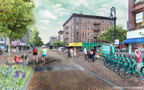 A downtown area with pedestrians an bicyclists enjoying the day.