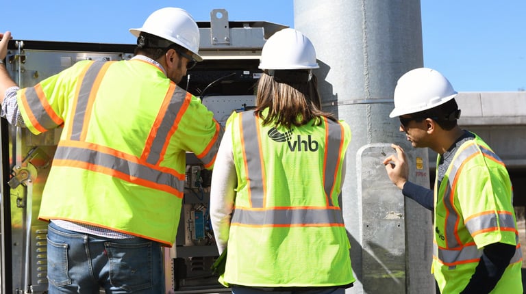 VHB team members review and test ITS equipment inside a roadside communications cabinet.