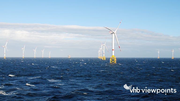 Eight wind turbines standing in the ocean.