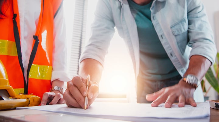 Three people representing contractor, designer, and owner collaborate on project plans. 